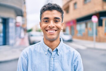 Young latin man smiling happy walking at the city.