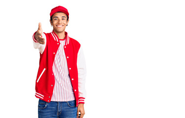 Young african amercian man wearing baseball uniform smiling friendly offering handshake as greeting and welcoming. successful business.
