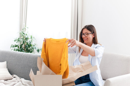 Young Woman Receiving Parcel At Home. Holiday Shopping Online And Unpacking Cardboard Box. Delivery Service During Covid Quarantine. Happy Girl Getting Gift. Lifestyle Moment.