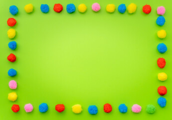 Frame with colorful small balls on green background.