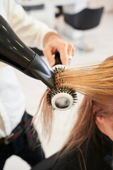 Naklejka premium Hairdresser drying woman's hair with hair dryer