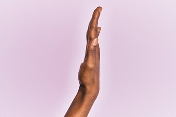 Arm and hand of black middle age woman over pink isolated background showing the side of stretched hand, pushing and doing stop gesture