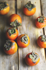 Selective focus. Macro. Persimmon on a wooden surface. Rustic style. Ripe persimmon. Autumn fruits.