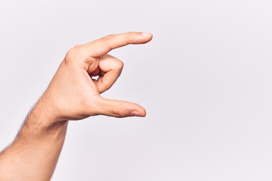 Close up of hand of young caucasian man over isolated background picking and taking invisible thing, holding object with fingers showing space