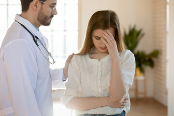 Difficult moment. Attentive compassionate tactful young male doctor supporting comforting stressed...