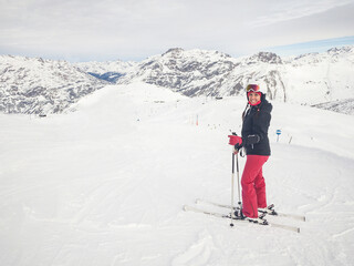 Fototapeta na wymiar Happy woman with ski on top of mountain slopes - Beautiful young woman enjoying ski holidays and having fun on the snow on a beautiful sunny winter day in Livigno - Sport and travel concepts