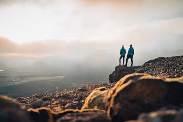 Couple travelers Man and Woman standing on cliff relaxing mountains and clouds aerial view Love and Travel happy emotions Lifestyle concept. Young family traveling active adventure vacations