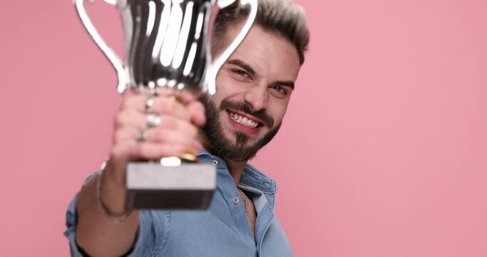 sexy casual man celebrating the victory bt raising his cup on pink background