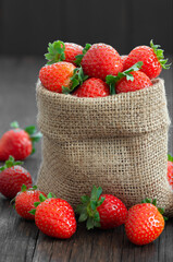 Fresh ripe harvested strawberries in burlap sack on wooden table, Garden summer fruit, strawberry, copy space ( Fragaria )