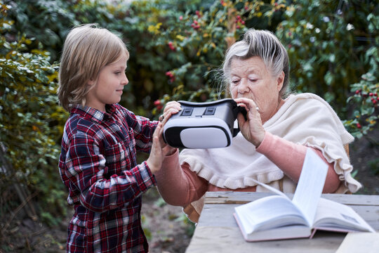 Child giving VR glasses to his granny