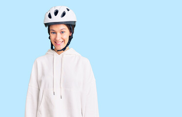 Beautiful brunette young woman wearing bike helmet and sporty clothes with a happy and cool smile on face. lucky person.