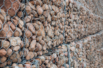 Cobblestone wall along the road - fortification of the river bank with stone and wire