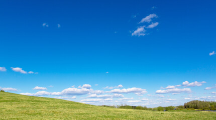 Green field and sun against a blue sky with clouds. The nature of Belarus. A beautiful place to travel and relax with your family. Can be used as a picture for interior decoration.