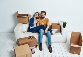 Fototapeta na wymiar Married couple on a white sofa in the room interior with boxes of communication things