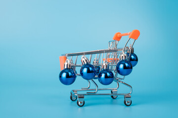 Christmas shopping concept. Close up photo of little mini push cart art with vivid color baubles...