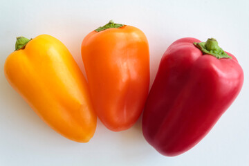Red pepper, orange pepper and yellow pepper on white background