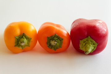 Red pepper, orange pepper and yellow pepper on white background