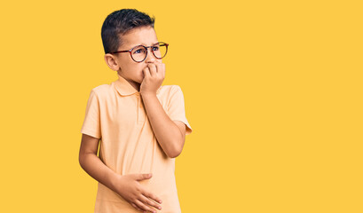 Little cute boy kid wearing casual clothes and glasses looking stressed and nervous with hands on mouth biting nails. anxiety problem.