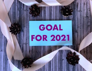 Goal for 2021 on a blue sticker on a wooden background.