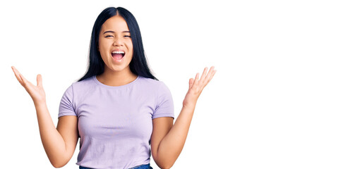 Young beautiful asian girl wearing casual clothes celebrating victory with happy smile and winner expression with raised hands