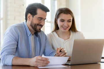 Effective work in pair. Glad happy diverse business partners young man and woman collaborate cooperate on paperwork project presentation, exchanging points of view, using laptop, engaged in process