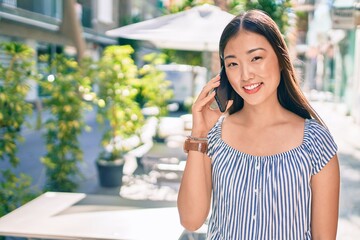 Young chinese woman smiling happy talking on the smartphone at street of city.