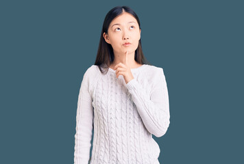 Young beautiful chinese woman wearing casual sweater thinking concentrated about doubt with finger on chin and looking up wondering