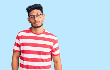 Obraz premium Handsome latin american young man wearing casual clothes and glasses looking sleepy and tired, exhausted for fatigue and hangover, lazy eyes in the morning.
