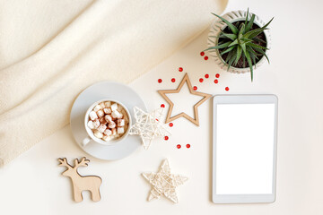 A digital tablet with a blank screen lies on a white table surrounded by flat wooden Christmas decorations