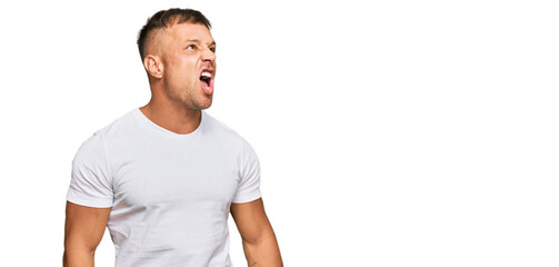 Handsome muscle man wearing casual white tshirt angry and mad screaming frustrated and furious, shouting with anger. rage and aggressive concept.