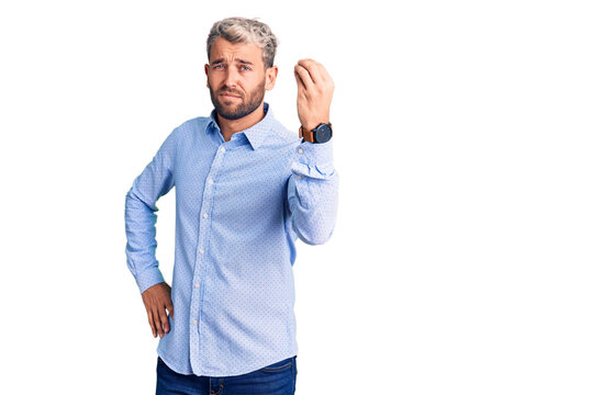 Young handsome blond man wearing elegant shirt doing italian gesture with hand and fingers confident expression