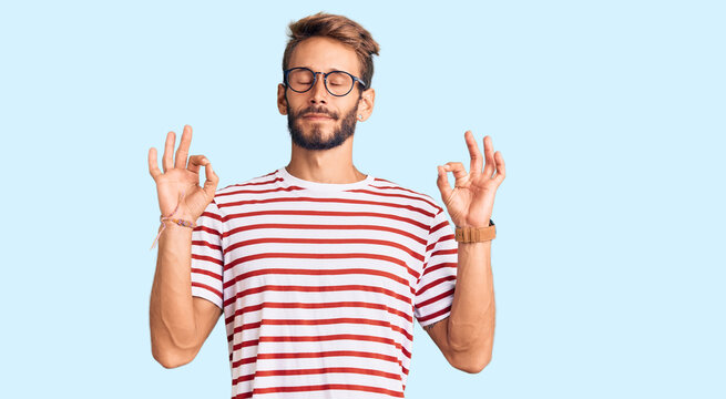Handsome blond man with beard wearing casual clothes and glasses relaxed and smiling with eyes closed doing meditation gesture with fingers. yoga concept.