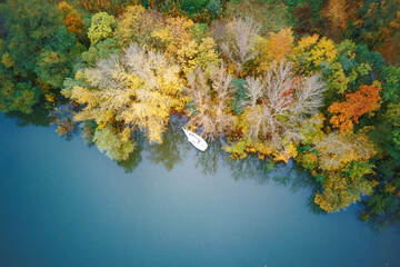 Fototapeta na wymiar Small sailing yacht and lots of green and yellow trees, autumn, view from the height