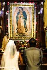 Just married kneeling sucking the virgin of guadalupe in the church