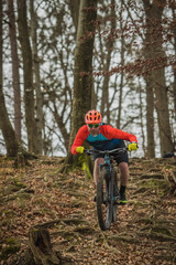 Biker charging downhill with a modern lightweight electric bicycle or mountain bike in autumn or winter setting in a forest.