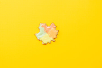 Sweet homemade leaf cookie with icing isolated on yellow background minimal flat lay composition.