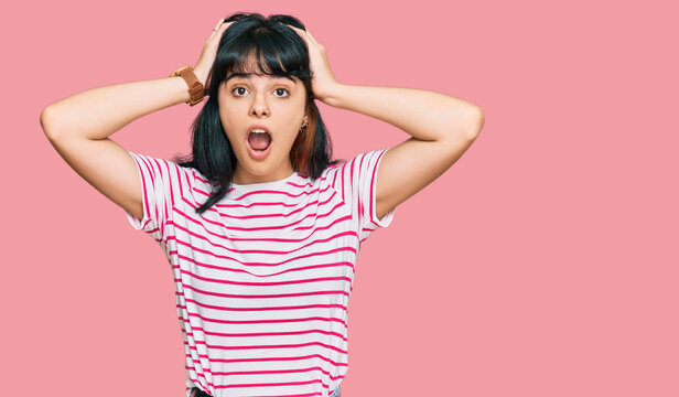 Young hispanic girl wearing casual clothes crazy and scared with hands on head, afraid and surprised of shock with open mouth