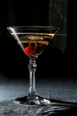 A martini glass with cherry on dark background