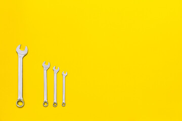 Four metal wrenches of different sizes isolated on a red background with copy space. Conceptual idea of the differences between: boss and employee, older and younger, big and small, parent and child