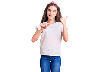 Obraz na płótnie Canvas Cute hispanic child girl wearing casual white tshirt pointing to the back behind with hand and thumbs up, smiling confident