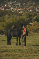 A black horse and a a man on a sunny autumn day.