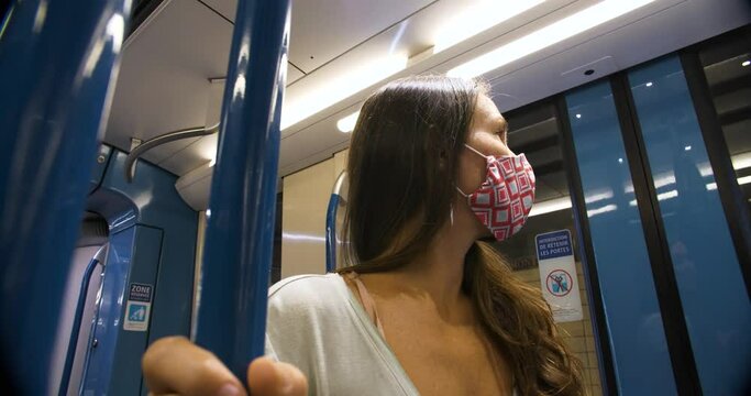Montreal Metro Subway, Montreal, Quebec - August 9, 2020: Young woman wearing covid-19 protective face mask in train looking at station during halt