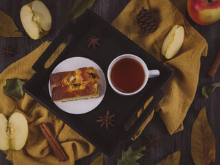breakfast with coffee.

Apple pie with tea in a black tray on the table with apples and cinnamon, top view close-up.