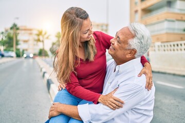 Middle age hispanic couple smiling happy and hugging sitting on the bench.