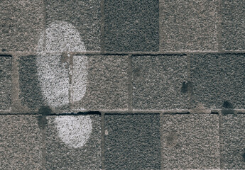 Fototapeta premium footprint on the sidewalk.White footprint from shoes on the left on dark gray paving slabs with space for text on the right, top view close-up.