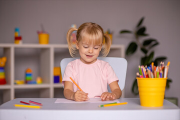 Cute little child girl writing with pencils in day care center