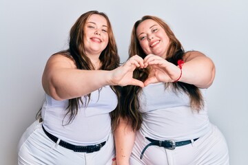Plus size caucasian sisters woman wearing casual white clothes smiling in love doing heart symbol shape with hands. romantic concept.