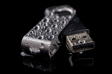 USB flash drive with water drops on the table. Electronic data storage device poured over with...