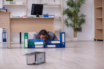 Young male employee and mousetrap in the office