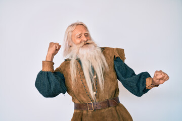 Old senior man with grey hair and long beard wearing viking traditional costume dancing happy and cheerful, smiling moving casual and confident listening to music
